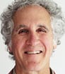 Photo headshot of smiling author DC with grey fluffy hair